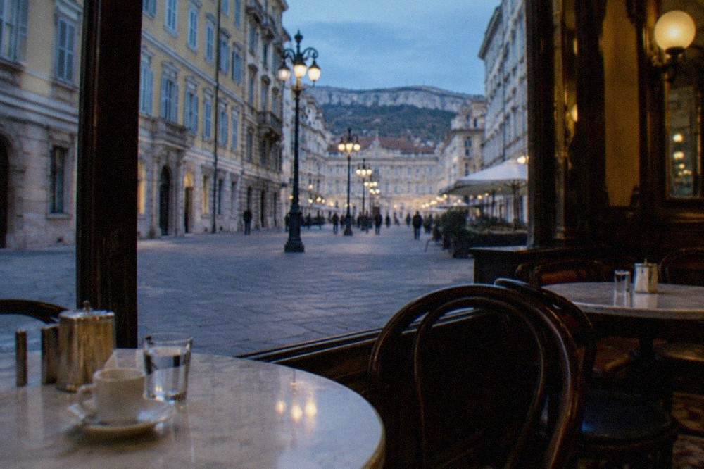 A historic Trieste café interior with marble tables, newspapers and mirrored walls