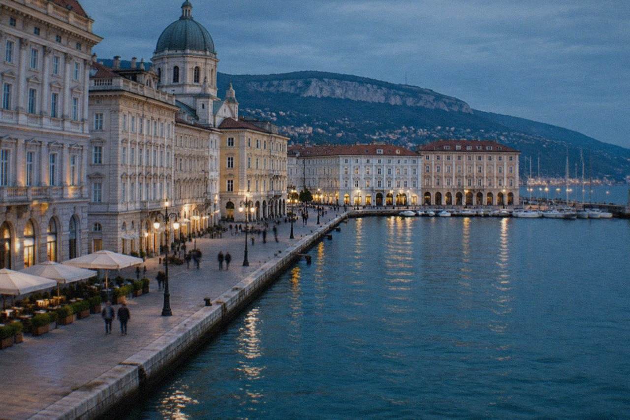 The seafront of Trieste, Italy, with the tall dome of a church and elegant Habsburg-era buildings along the waterfront