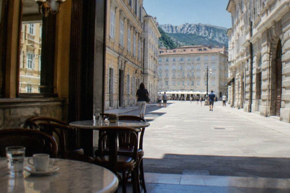A historic café interior in Trieste with marble tables and mirrored walls