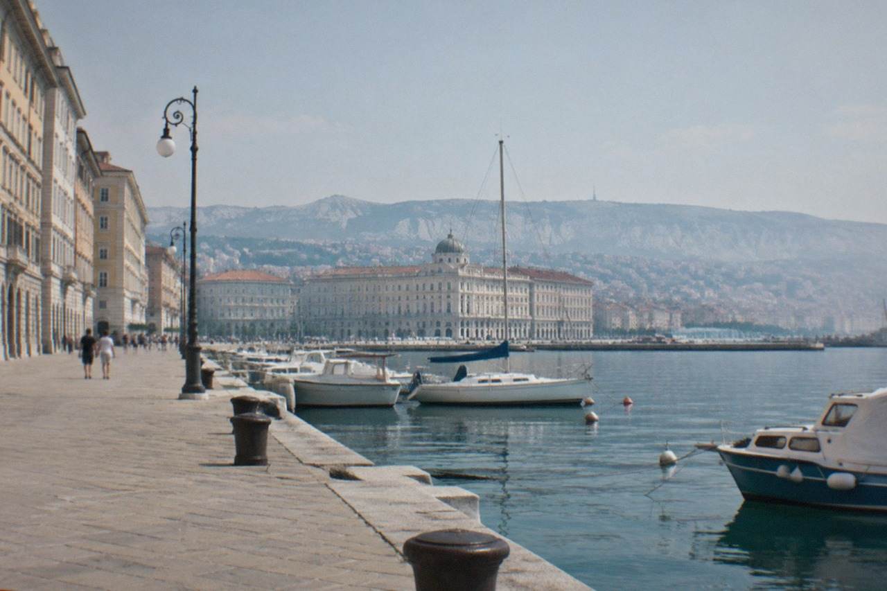The seafront of Trieste, Italy, on a calm morning with the shoreline piazza and moored boats along the water
