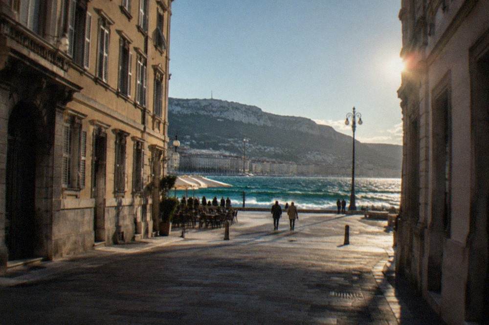 Waves breaking along the Trieste seafront under a clear windy sky