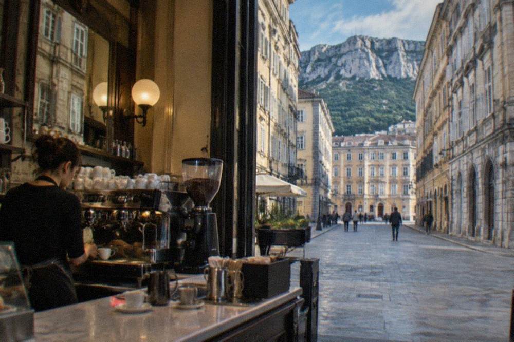 A barista serving espresso at the counter of a historic café in Trieste, Italy