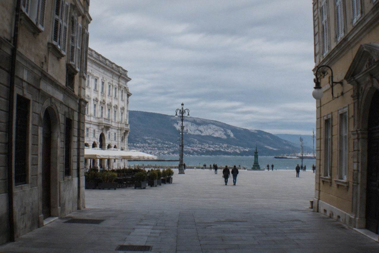 Wide seafront square with neoclassical facades and open water beyond
