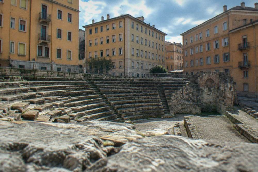The Roman theatre of Trieste seen from the street with apartment buildings rising behind the ancient stage