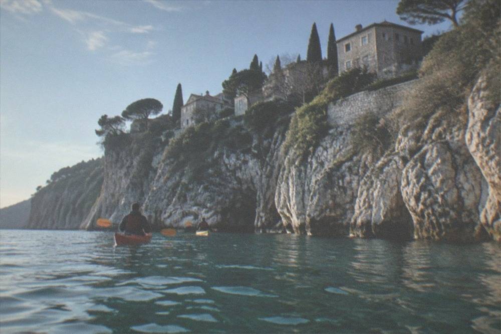 Kayaks paddling close to white cliffs above clear green water