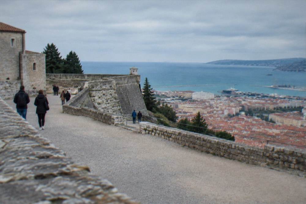Visitors walking the stone ramparts of San Giusto Castle above the rooftops of Trieste