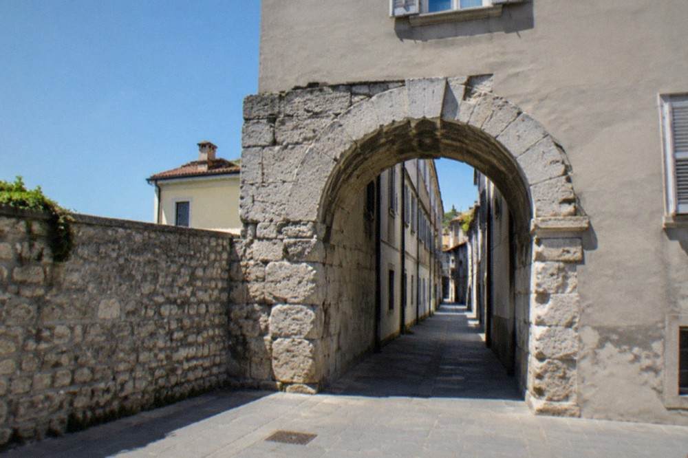 Close view of weathered Roman stonework forming a rounded archway in Trieste's old town