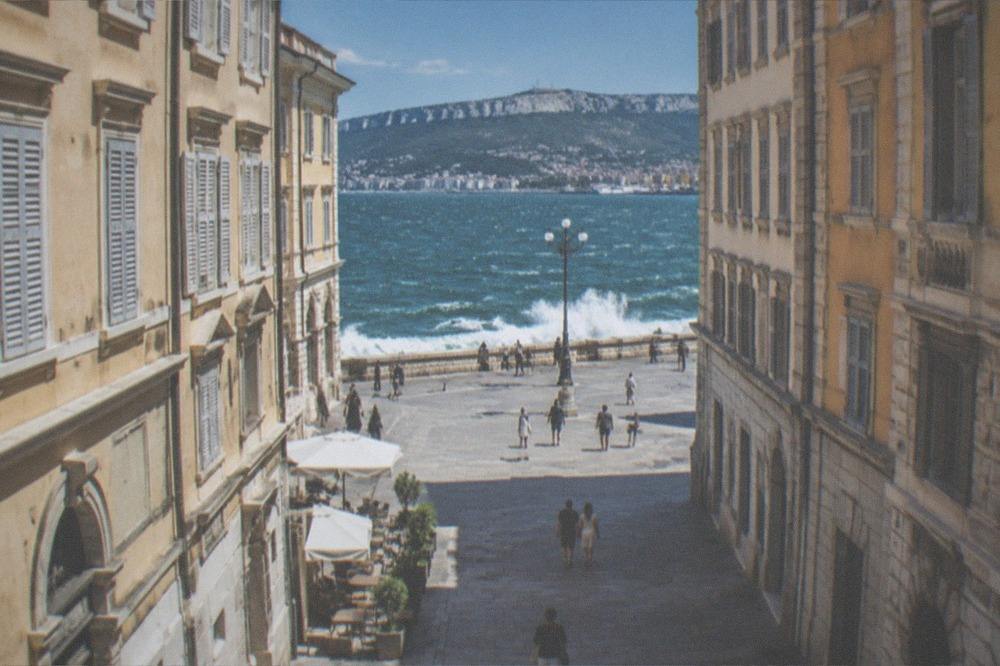 White-capped Adriatic waves breaking against a seafront wall under a clear windy sky in Trieste