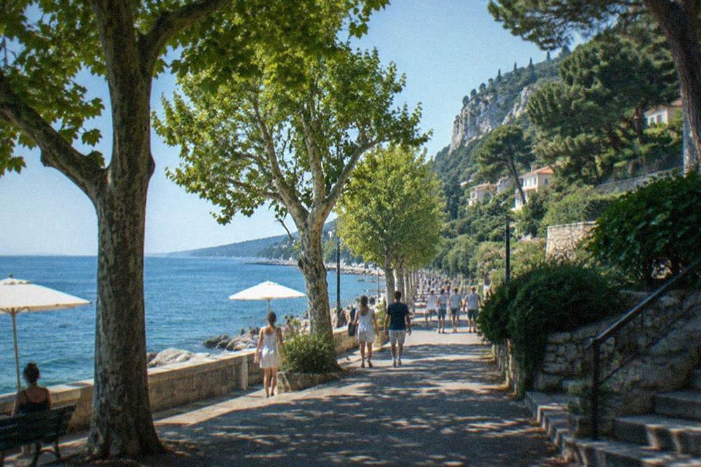 The Barcola promenade on a summer afternoon with parasols, plane trees and people walking along the seafront