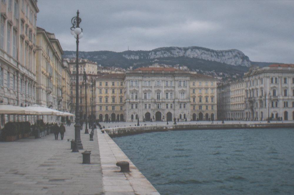 A wide seafront square with grand buildings facing the sea in Trieste, Italy