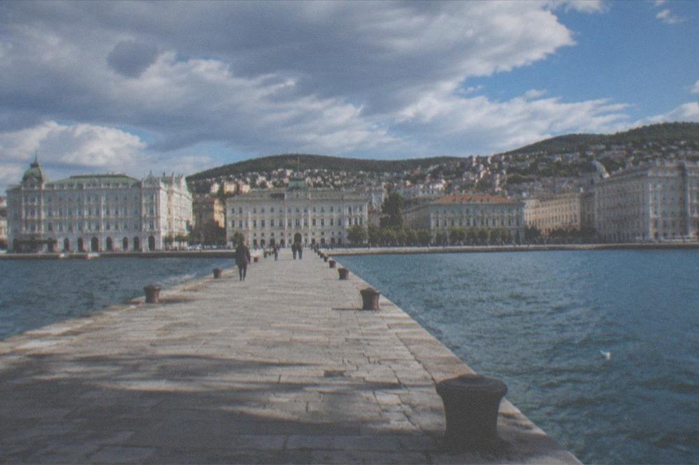 Steep narrow old-town lanes rising behind an elegant seafront square