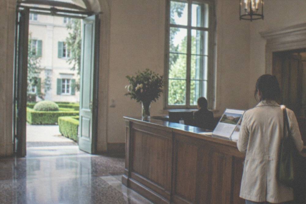 A museum ticket desk in a historic Triestine building with a visitor reading an information panel