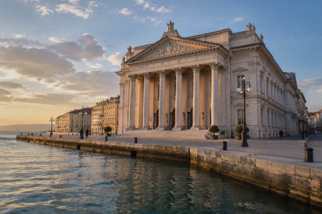 The ornate facade of an Italian opera house on a Trieste street in warm evening light