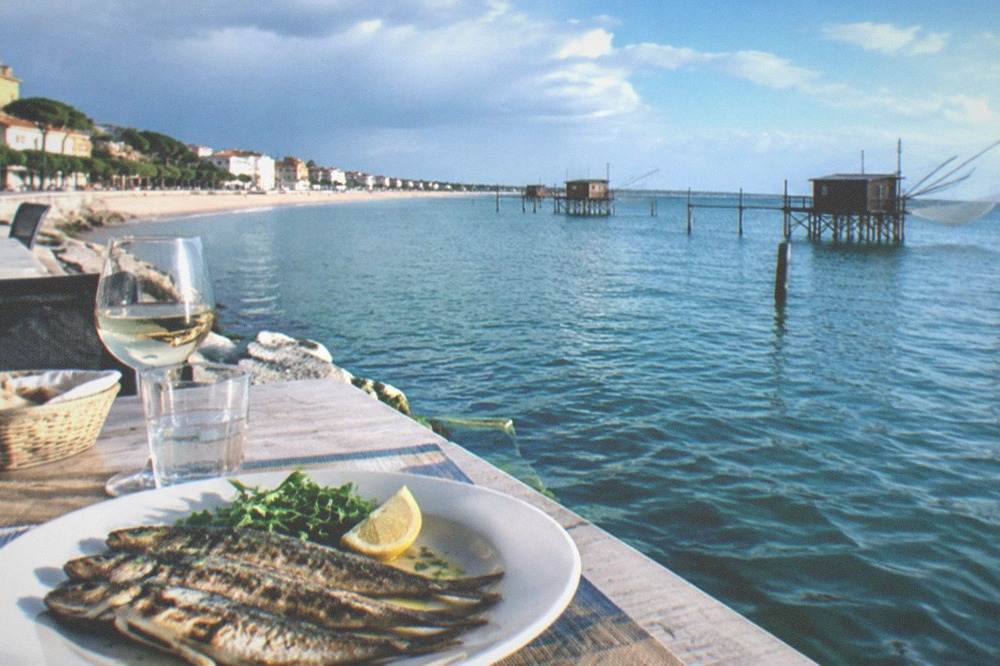 A plate of grilled lagoon fish with lemon on a restaurant table by the water