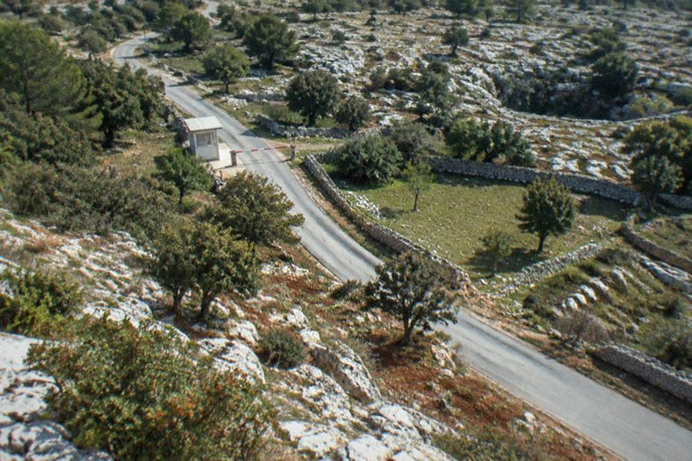 A rural border road on the Karst plateau with a small Schengen border sign