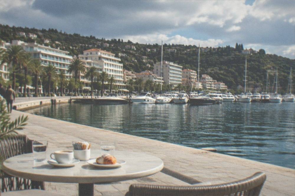 An outdoor cafe table with coffee and a pastry on a sunlit square