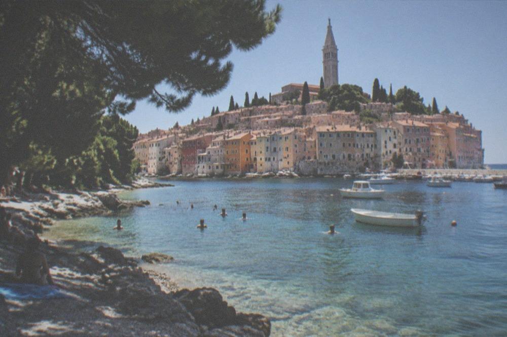 Swimmers and small boats in clear water on an Istrian beach in summer