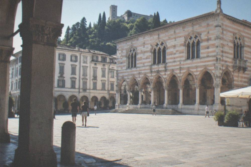 Ornate gothic loggia building with striped stonework facing a square in Udine