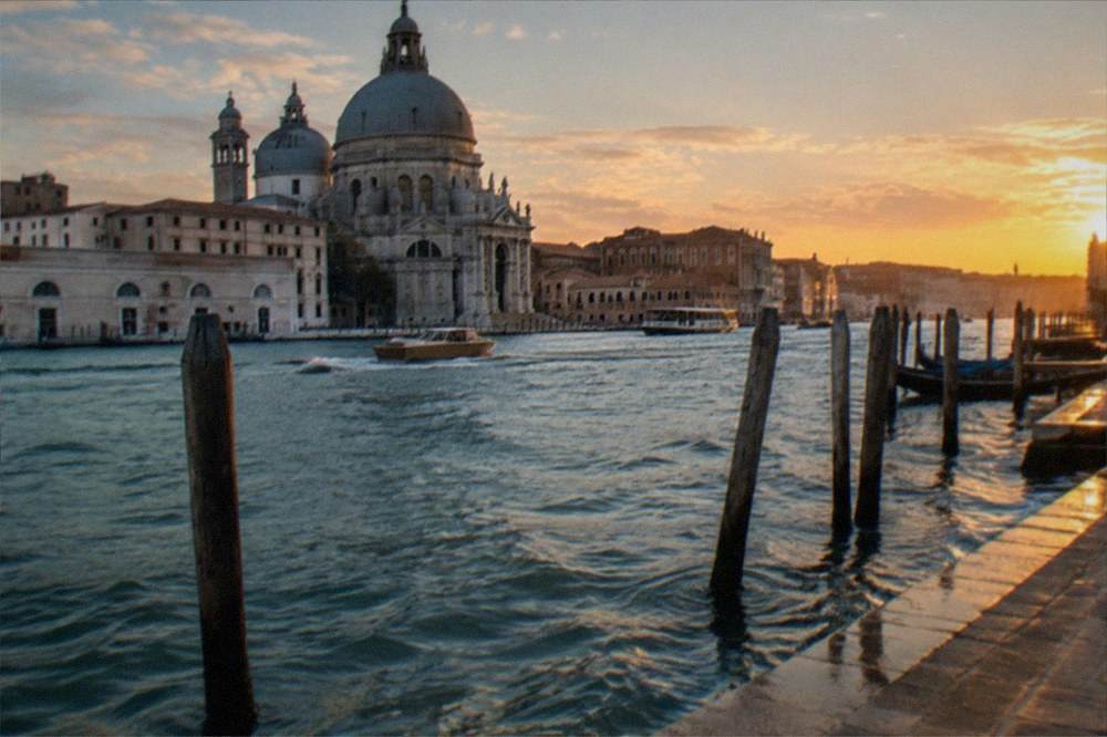 A grand seaside square with ornate buildings facing the water at dusk