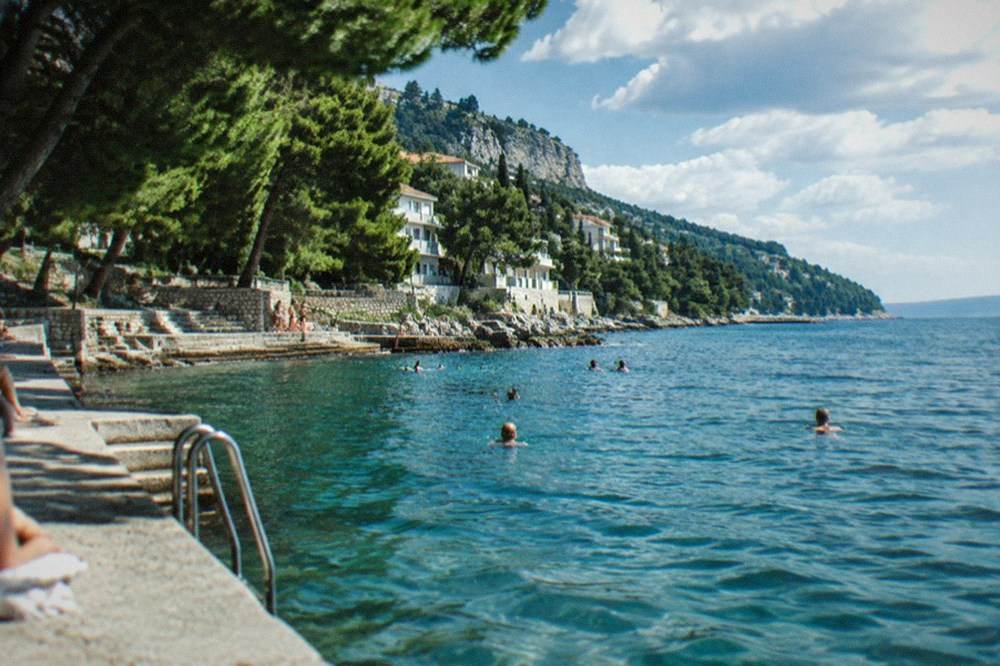People swimming from the paved seafront at Barcola in Trieste on a warm summer afternoon