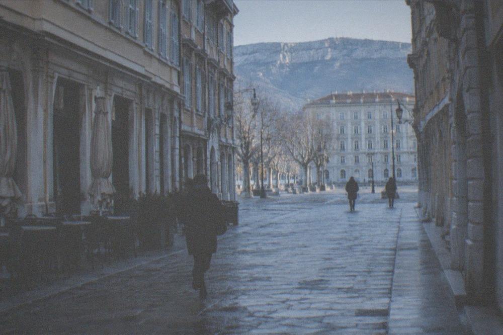 A quiet winter morning in the old town of Trieste with empty cobbled streets and closed café tables