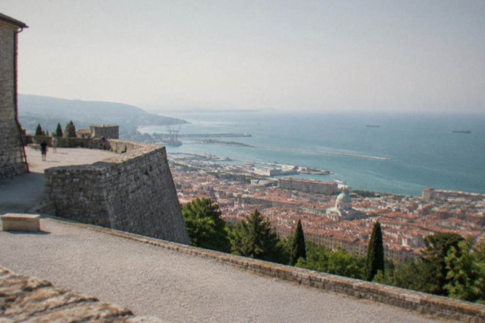 The ramparts of San Giusto castle in Trieste with views over red rooftops toward the Adriatic