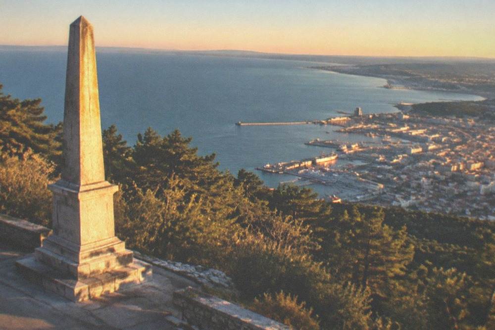 The Opicina obelisk above Trieste with the gulf and city spread below under a clear sky