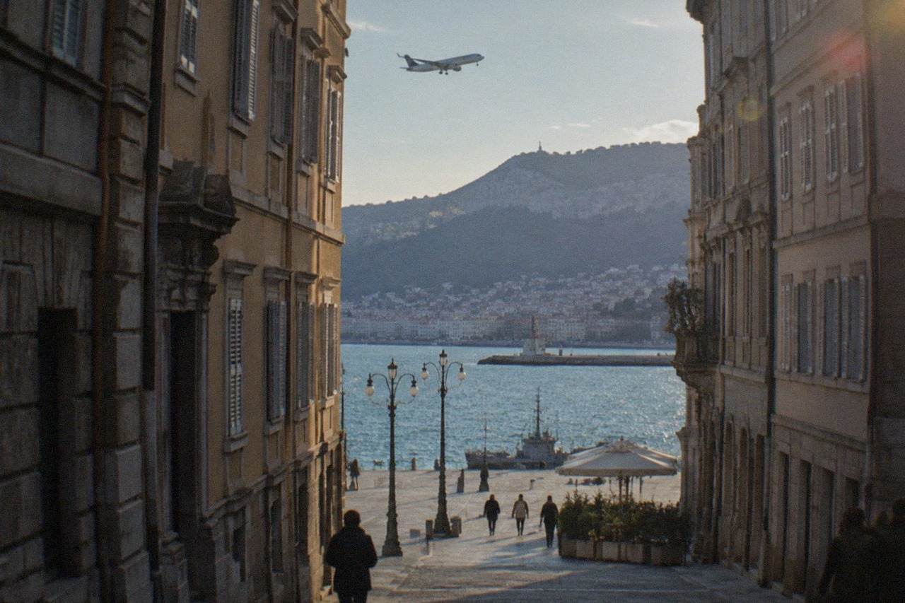 A plane descending over the Adriatic coastline near Trieste with hills behind the city