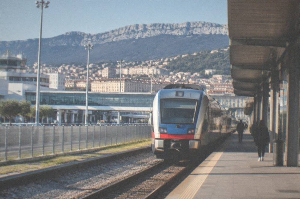 A regional train waiting at a platform shelter beside Trieste Airport terminal