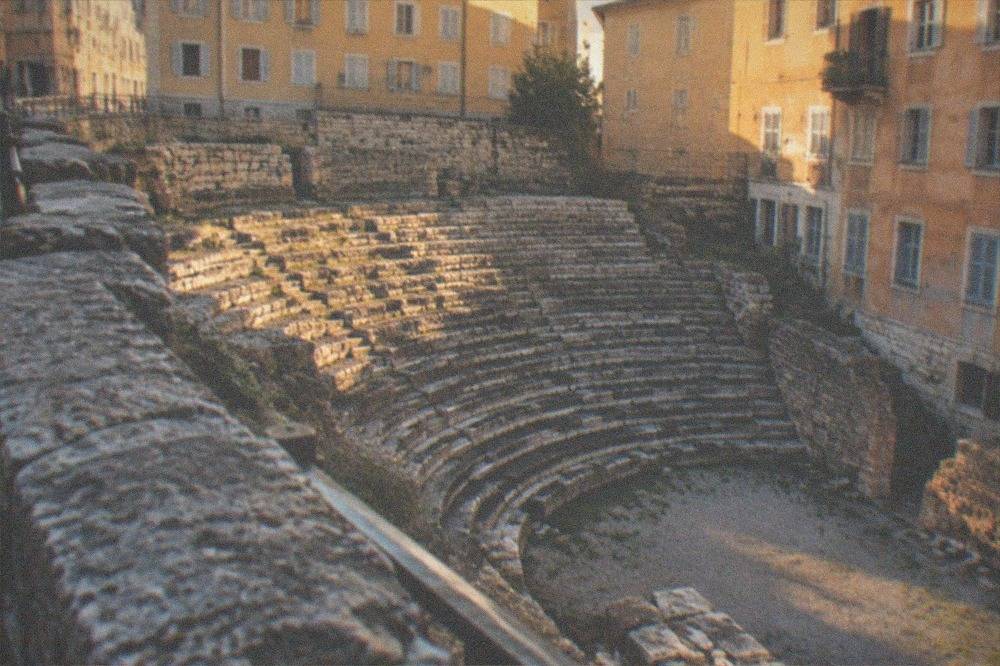 The ancient stone tiers of a Roman theatre seen from the street above