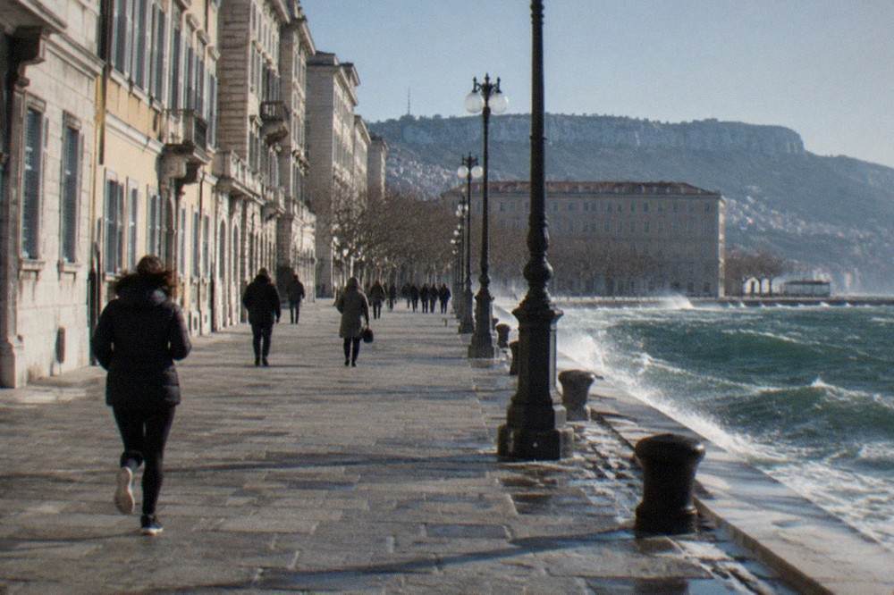 Choppy grey-green water along the Trieste seafront with spray blowing off the wave tops