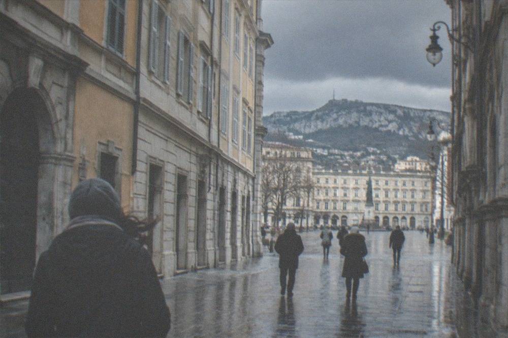 Dark autumn clouds over the rooftops of Trieste with wet streets reflecting the buildings