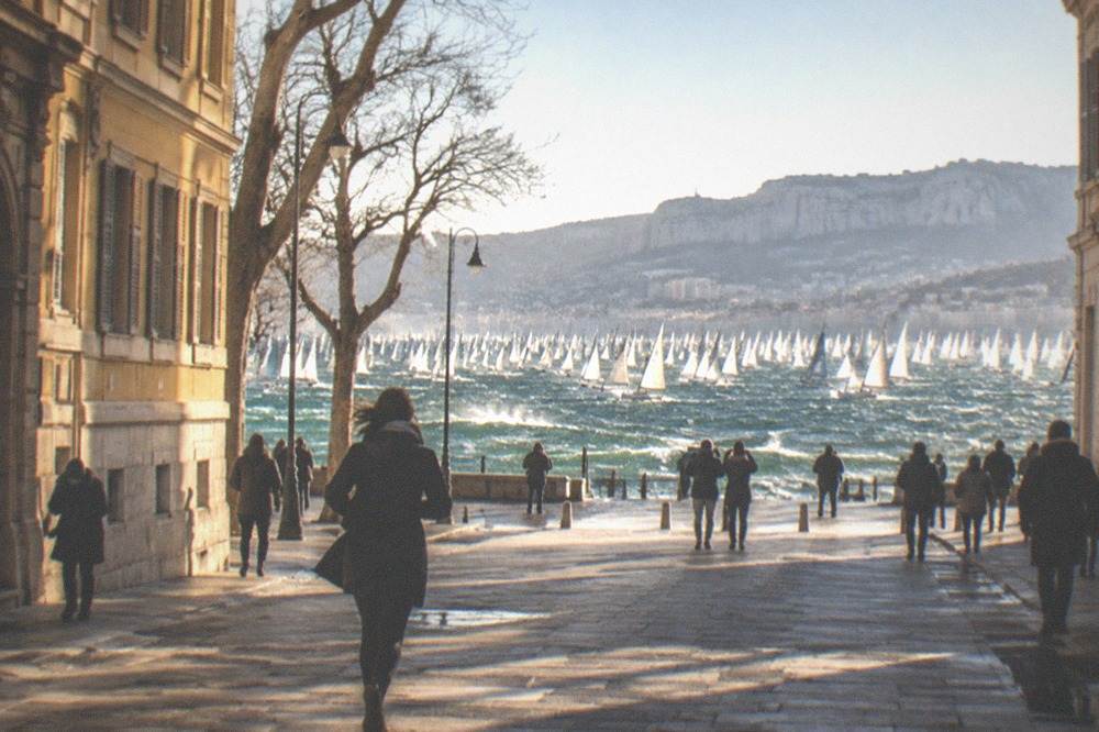 Thousands of sailboats crowded on the start line of a regatta in a wide gulf