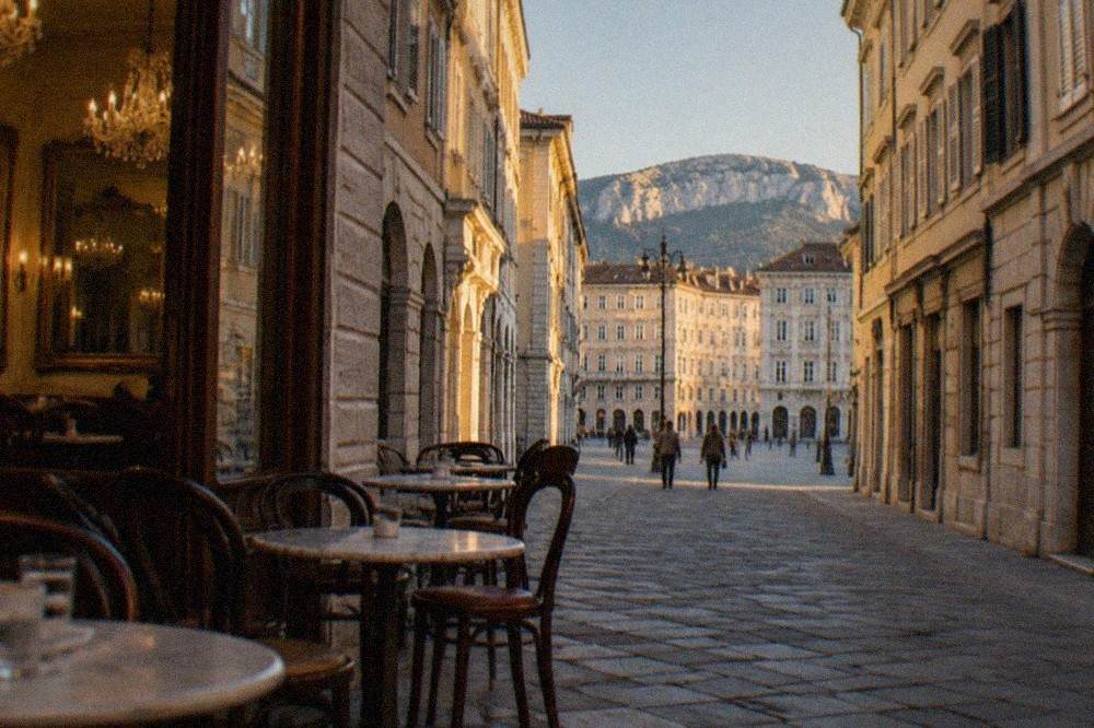 A historic café interior in Trieste with chandeliers, mirrors and small marble tables