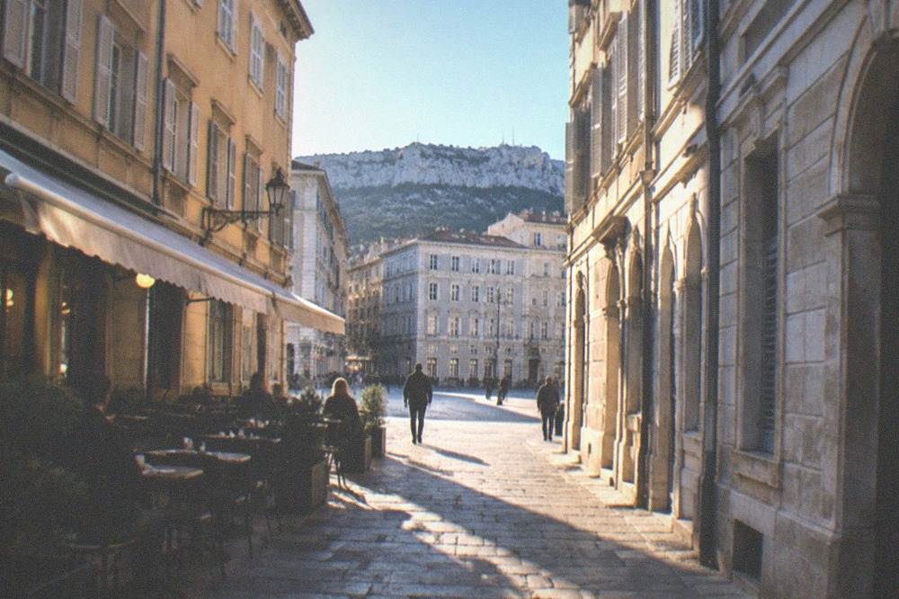 A narrow old-town street in Trieste with a small cafe bar spilling light onto the cobbles