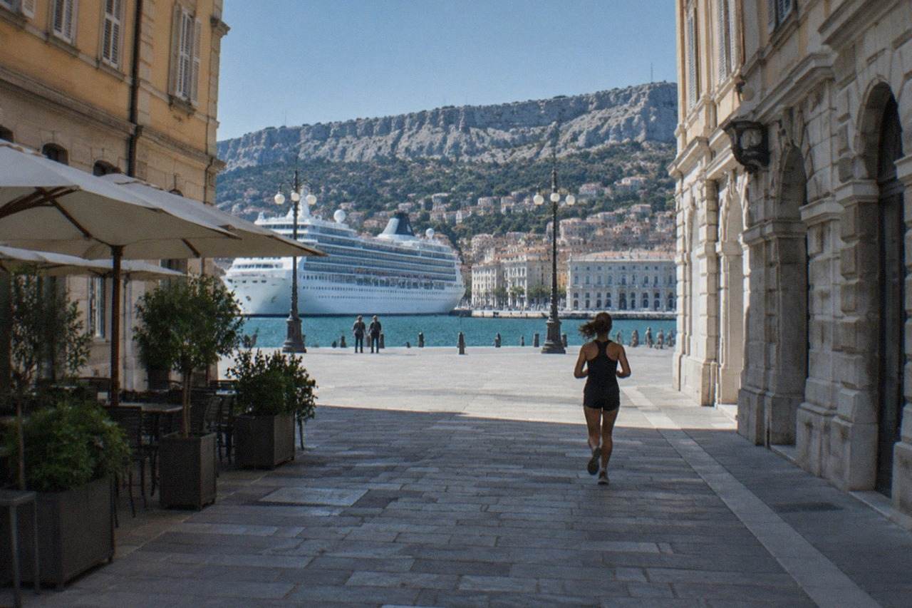 A cruise ship tied up at the Trieste waterfront with the city's grand squares and hills behind it