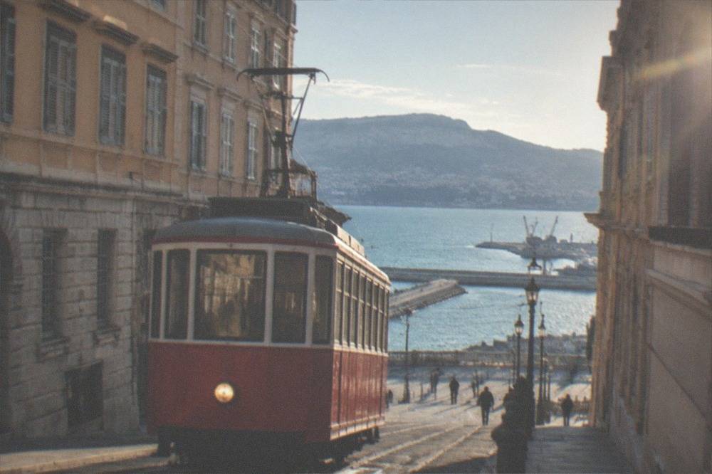 A red Trieste tram climbing the steep hillside toward Opicina with the sea below