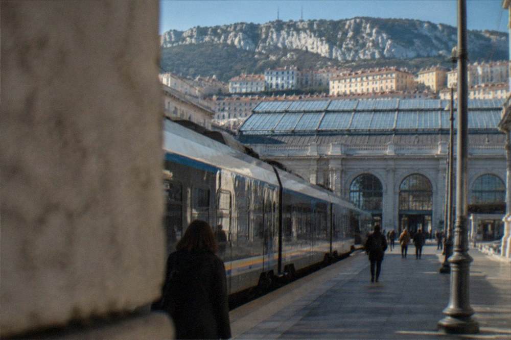 A regional train at Trieste Centrale station with the station hall behind it