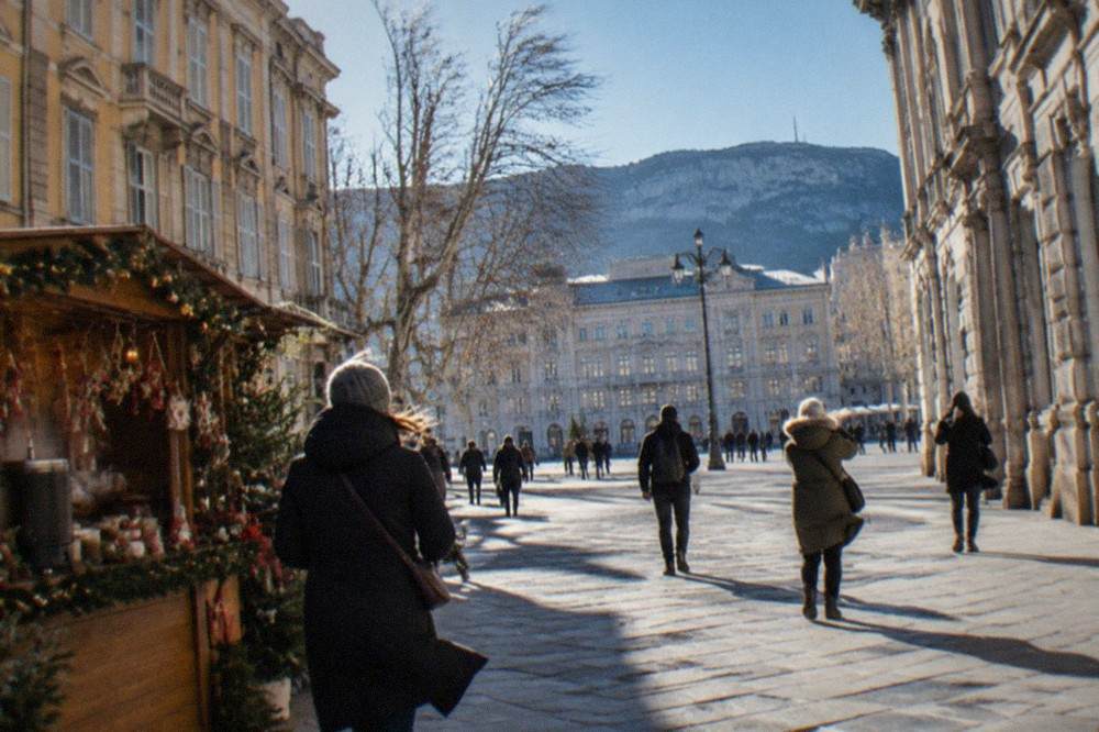 A wooden stall at a Christmas market selling mulled wine and decorations in front of ornate Habsburg-era buildings