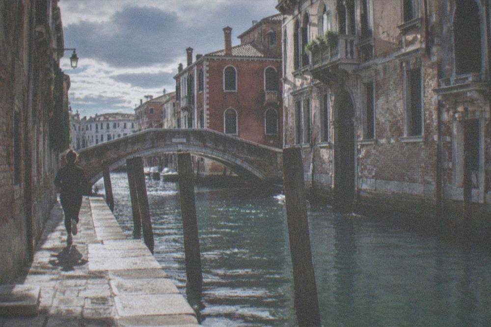 A canal in Venice with a bridge and mooring poles in morning light