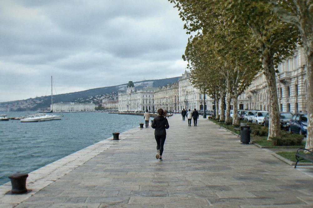 Wide seafront promenade in Trieste with a few strollers along the water