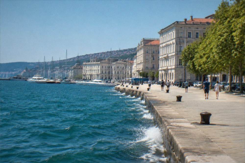Waves breaking along a stone seafront promenade under a clear sky