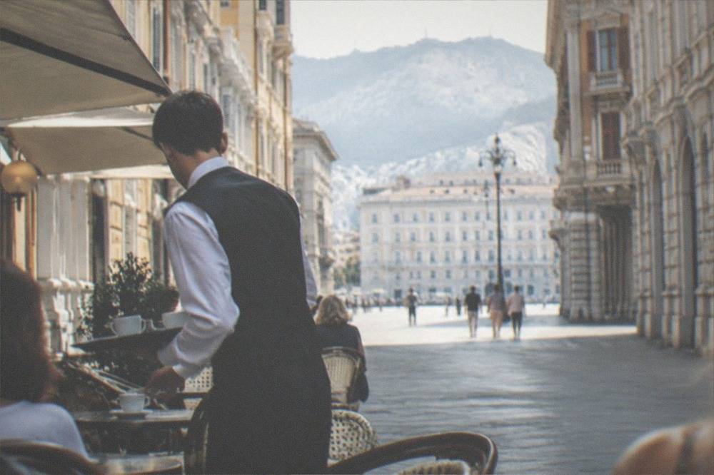 A waiter serving coffee in a grand historic Trieste café