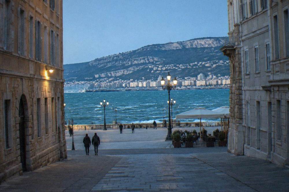 Whitecaps on the Gulf of Trieste under a clear sky with the city skyline behind
