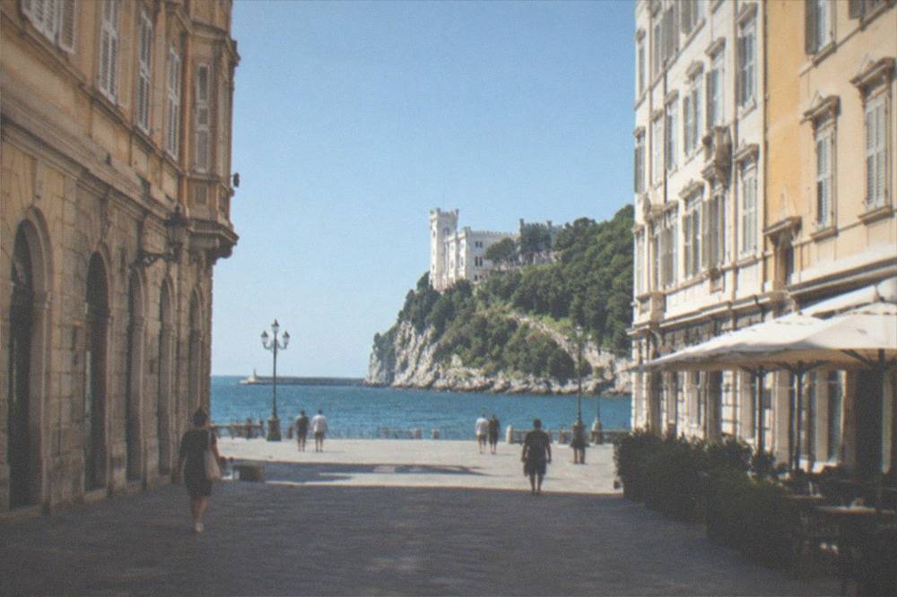 A white castle on a clifftop above the Adriatic with a green park around it