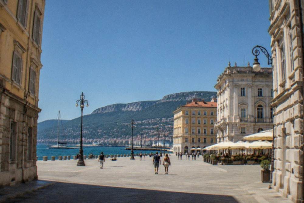 A wide square beside the sea with ornate facades and open sky